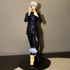 Action figure with a black outfit and blue hair on a stand against a plain background